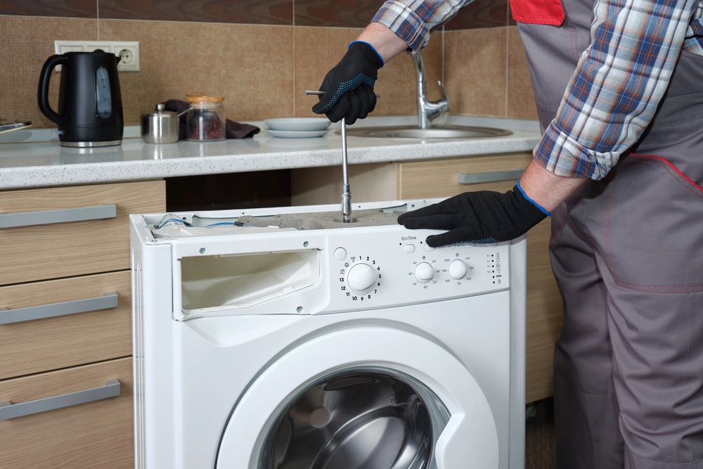 Professional Washing Machine Repair vs. DIY Fixes Image of a service technician in uniform repairing a household washing machine, featuring Accurate Appliance Repair and highlighting the advantages of professional washing machine repair over DIY fixes.